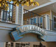 A building exterior with an iron balcony railing and a large “Village Fair” sign for restaurants and shops.
