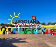 A LEGO Land California entrance sign with colorful LEGO figures and a huge “LEGO LAND” display under a blue sky.